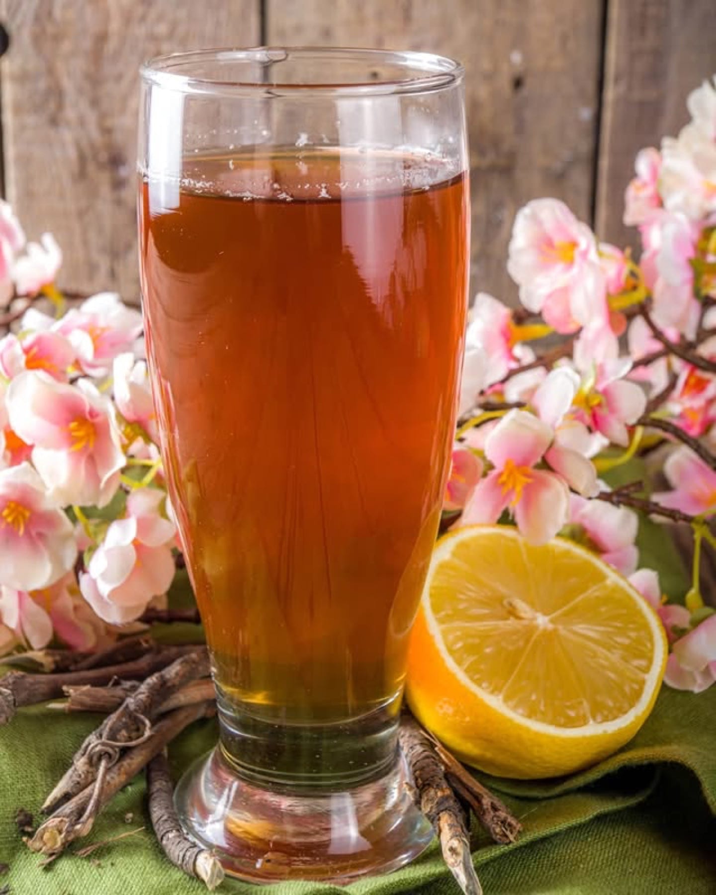 A spring drink with cherry blossoms and lemon, on a warm wood surface