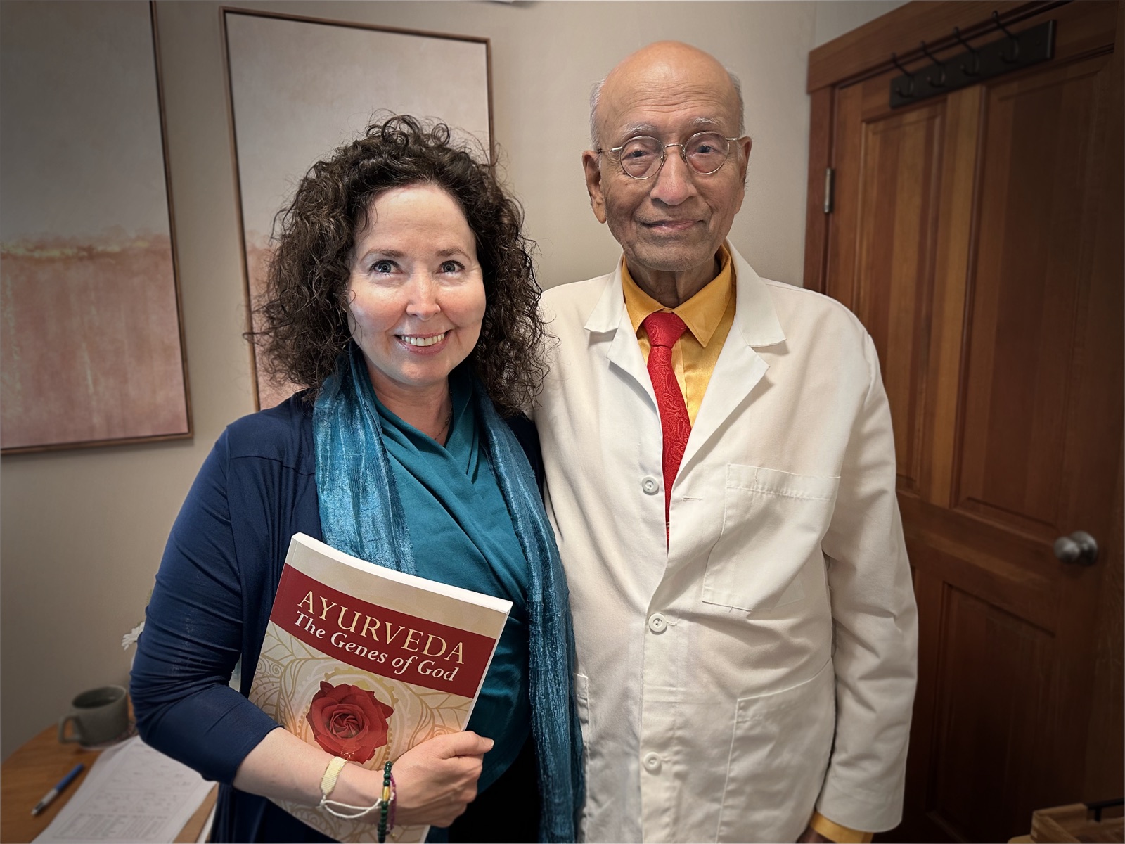 Susan Hiera Bass standing with her teacher Dr. Vasant Lad, holding a copy of her book Ayurveda: The Genes of God